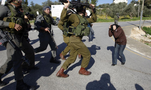SAMMENST�T: En israelsk soldat l�fter sitt v�pen mot en palestinsk kvinne under sammenst�t i byen Nabi Saleh p� Vestbredden. Foto: REUTERS/Ammar Awad/Scanpix