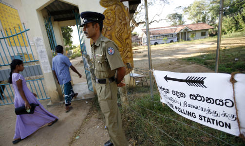 HOLDER VAKT: En politimann holder vakt utenfor et valglokale i Medamulana p� Sri Lanka tirsdag. Foto: REUTERS/SCANPIX