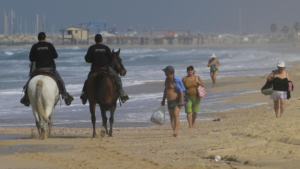 FANT SPRENGSTOFF: Israelsk ridende politi og surfere p� stranden utenfor byen Ashkelon, der det mandag ble funnet sprengstoff som trolig stammer fra palestinske grupper p� Gazastripen. Foto: SCANPIX