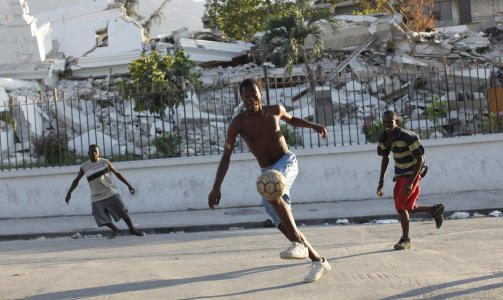 SAMMENRAST JUSTISSYSTEM: Tre unge gutter spiller fotball utenfor det sammenraste justisdepartementet. Foto: REUTERS/Kena Betancur/Scanpix