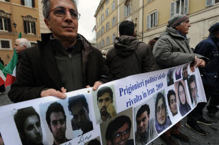 OPPOSISJONELLE BAK MURENE: Demonstranter viser fram bilder av mennesker som er arrestert i Iran. Foto: AFP PHOTO/ANDREAS SOLARO/SCANPIX
