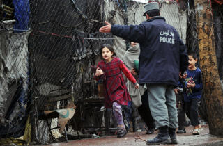 ADVART: En afghansk jente blir dirigert av en politimann. Over h�ytalere ble Kabuls innbyggere bedt om � holde seg innend�rs etter selvmordsangrepet. Foto: AFP PHOTO/Massoud HOSSAINI/SCANPIX