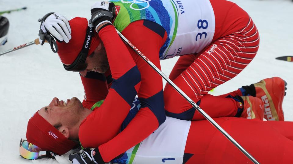 GRATULERTE GULLGUTTEN: Odd-Bj�rn Hjelmeset kastet seg umiddelbart over Petter Northug i m�lomr�det. Foto: EPA