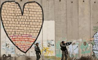 B�DE MUR OG SIKKERHETSBARRIERE: Israelsk grensepoliti ved den omstridte sikkerhetsmuren, bildet er tatt ved sjekkpunktet Kalandia. Foto: AP/Muhammed Muheisen