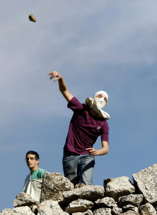 STEIN MOT PALESTINERE: J�diske nybyggere kaster stein mot palestinere i n�rheten av bosetningen Halamish p� Vestbredden. Den iraelske h�ren rykket inn i januar i �r for � skille bosettere og palestinere som kastet stein p� hverandre. Foto:  REUTERS/Baz Ratner