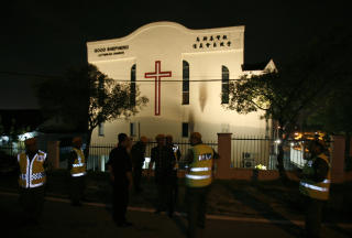 FLERE KIRKER ANGREPET: Politiet utenfor en kirke i Petaling Jaya ved Kuala Lumpur i januar. Ni kirker og flere skoler var satt i brann. Denne kirken fikk bare to svarte sotflekker p� veggen til h�yre. Foto:  REUTERS/Bazuki Muhammad