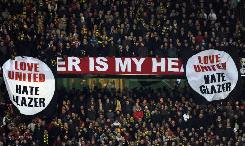 GA OPP � FJERNE BANNERE: Disse to anti-Glazer-bannerne ble hengende p� Stretford End uten at vakter greide � f� dem vekk. En stadionansatt gjennnom 19 �r er imidlertid sparket for � ha returnert et konfiskert banner til en supporter. Foto: AFP PHOTO/GIUSEPPE CACACE