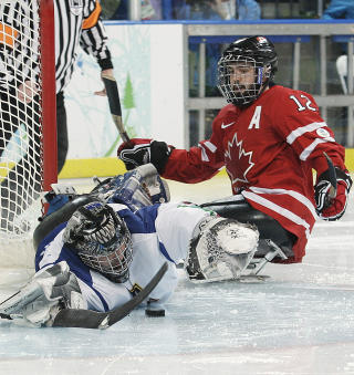  �PNINGSRUNDEN:  Fra den  andre kampen i kjelkehockey �pningsrunden  i Paralympics i Vancouver l�rdag. Canadas Greg Westland i r�dt i angrep mot Italia og m�lvakt Santino Stillitaro. Canada vant 4-0.  FOTO: REUTERS/SCANPIX.