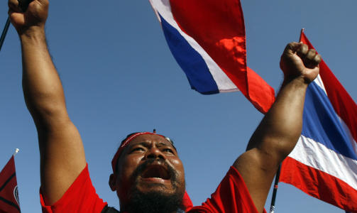 KREVER AT REGJERINGEN G�R AV: En av de s�kalte r�dskjortene veiver med det thailandske flagget under en demonstrasjon i Bangkok s�ndag. Tidligere statsminister Thaksin Shinawatras tilhengere krever at regjeringen g�r av. Foto: REUTERS / Kerek Wongsa / SCANPIX