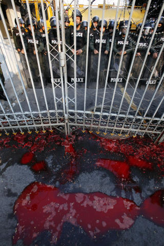 KLARE: Oppr�rspoliti st�r klare bak sperringene som avskj�rer demonstrantene fra � entre regjeringsbygget i Bangkok. Utenfor ligger blodet i store dammer. Foto: Reuters