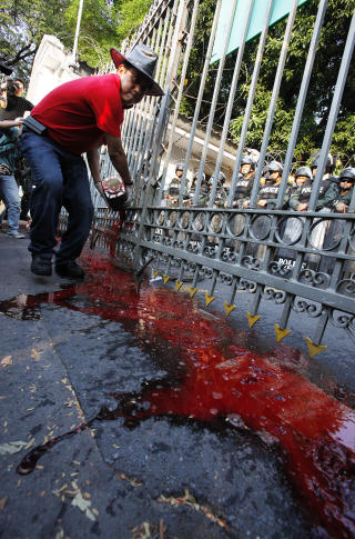 T�MMER UT: En demonstrant t�mmer menneskeblod utover gata utenfor regjeringsbygget. Foto: Reuters