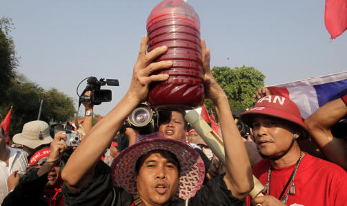 SAMLET BLOD: En tilhenger av tidligere statsminister Thaksin Shinawatra holder en flaske med blod over hodet. Blodet har de tappet og samlet fra demonstranter i l�pet av dagen i dag. Foto: AP