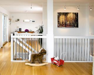 TILPASNINGER: Huset kom med eikeparkett og hvite vegger. P� grunn av barna har Mette og �smund montert en grind fra Ikea foran den bratte trappen. Bildet p� veggen er fra skogen utenfor huset, og er tatt av Mette. Foto: B�rd J�rgensen