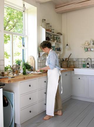 HOVEDROMMET: Kj�kkenet er husets hjerte. P� den solide arbeidsbenken lager Camilla Jensen retter til familien og for kokeb�ker, for tiden hoder hun p� med en frokostbok. Kj�kkeninnredningen har mannen snekret, f�r den kom p� plass brukte de gamle vinkasser. Vasken er fra Ikea. Foto: Espen Gr�nli