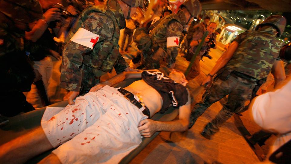 RAMMET USKYLDIGE: En av de skadde b�res vekk av medisinsk personell. Det har v�rt uro i Thailands hovedstad Bangkok i flere uker. Foto: AP/Vincent Yu
