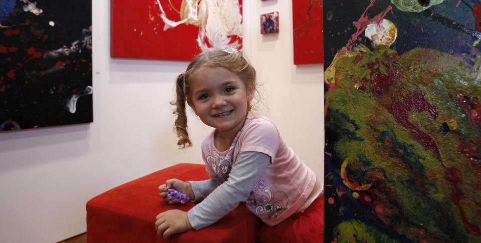 OMSTRIDT: Aelita Andre er avbildet foran sine egne bilder som vises under Art Melbourne 2010-utstillingen. Kunstneren er tre �r gammel og strever enn� med � knytte sine egne skolisser, men hun har allerede rukket � f� vist fram sine bilder over hele verden.  Foto: REUTERS/SCANPIX