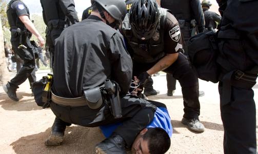ARRESTASJONER: Her blir en mann arrestert etter at det ble kastet flasker etter Arizonas guvern�r Jan Brewer. (AP Photo/The Arizona Republic, Cheryl Evans/Scanpix)