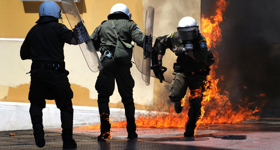 R�MMER FRA FLAMMENE: Her fors�ker de greske politimennene � komme seg unna flammene for�rsaket av en brannbombe. Foto: AFP PHOTO/SCANPIX