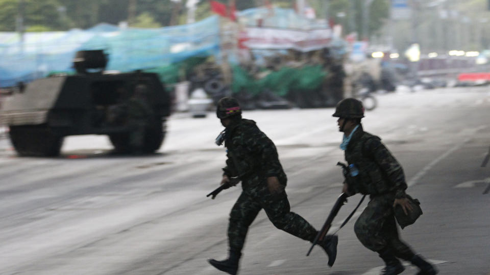  P� BARRIKADENE:  Regjeringssoldater l�per gjennom skuddlinjen i Bangkok i fomiddag mens pansrede milit�rkj�ret�y har parkert p� demonstrantenes sperringer. FOTO: DAMIR SAGOLI, REUTERS/SCANPIX.