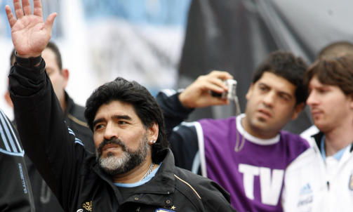 SPILTE IKKE: Diego Maradona vinker til fansen, mens Lionel Messi i bakgrunnen lar seg avbilde sammen med en TV-fotograf. Messi sto over med en s�rskade han p�dro seg p� trening fredag, men Argentina slo likevel Canada 5-0. Foto: Santiago Pandolfi, Reuters/Scanpix