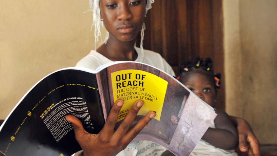 MORL�S: Lille Maya fra Sierra Leone mistet moren sin under f�dselen. Her sitter hun i tantes armkrok som leser en rapport fra Amnesty om m�dred�delighet i det vest-afrikanske landet. Foto: AFP