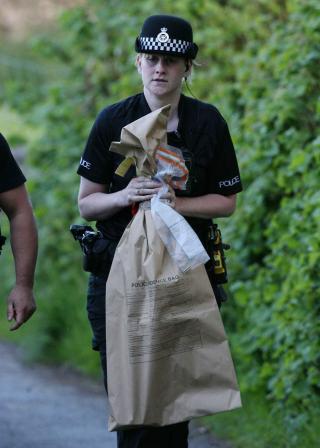 TO V�PEN: En polititjenestekvinne fra Cumbrian Police med et beslag, antakelig et av de to skytev�pnene, ved skogholtet der Bird tok sitt eget liv. Foto: EPA/Lindsey Parnaby