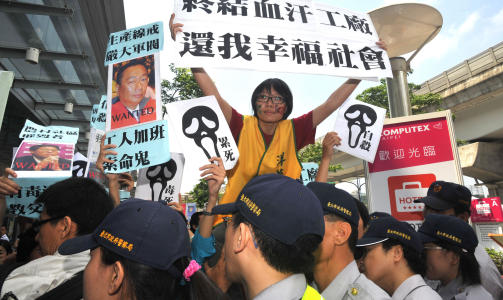 PROTESTER: Disse demonstrantene utenfor en teknomesse i Taipei holder opp skilt som sider Kapitalistene dreper folk, og holder opp bilder av Foxconn-sjef Terry Gou. Foto: AFP PHOTO/PATRICK LIN/SCANPIX