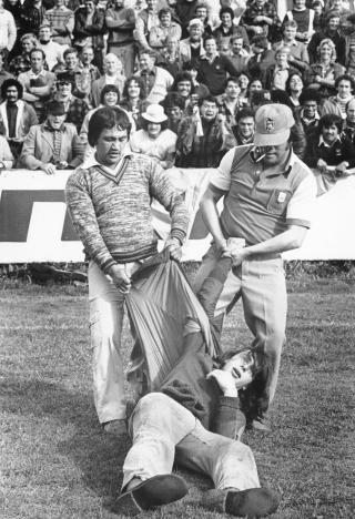 FORHATT, HVITT LAG: Det s�rafrikanske rugbylaget Springbok var forhatt for sin rasesegregering. Her drar et par supportere vekk en demonstrant, bildet er fra juli 1981. Foto: AP/New Zealand Herald