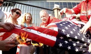 VISTE SIN AVSKY MOT EIERNE: Flere hundre Liverpool-fans m�tte opp utenfor Anfield i g�r for � vise sin st�tte til Rafael Benitez, og sin forakt mot de amerikanske eierne gjennom � brenne flagg. Foto: AP Photo/ Peter Byrne /PA