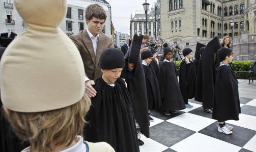 BLE UTFORDRET AV AP-POLITIKER: Magnus Carlsen spilte i dag med levende brikker mot stortingsrepresentant K�re Simensen (Ap), som fikk kyndig assistanse av sjakkpresident J�ran Aulin-Jansson. Etter 20 minutter m�tte de r�dgr�nne erkjenne nederlaget. 
Foto: Erlend Aas / Scanpix