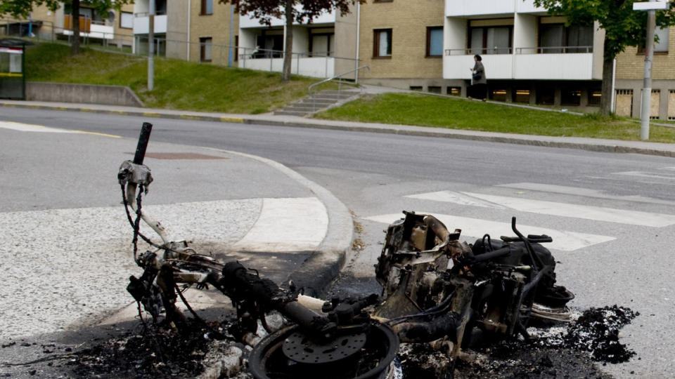 SYNLIG: En utbrent moped eller motorsykkel ligger igjen p� Rinkebystr�ket i Rinkeby etter urolighetene natt til onsdag. Noen mener uroen skyldes politibrutalitet. Andre skylder p� sosiale forhold og arbeidsl�shet. Foto: PONTUS LUNDAHL / SCANPIX