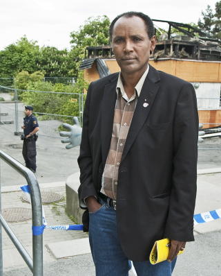 FORTVILT: Forstedet Rinkeby vest i Stockholm er som et bydelsfengsel, mener viseordf�rer Abebe Hailu i Rinkeby-Kista. If�lge ham er h�y arbeidsl�shet og mangel p� fritidsaktiviteter en viktig �rsak til uroen i bydelen. Her st�r han foran Rinkebyakademien, som ble fullstendig �delagt da det ble stukket i brann under oppt�yene. 
Foto: Johan Falnes / SCANPIX