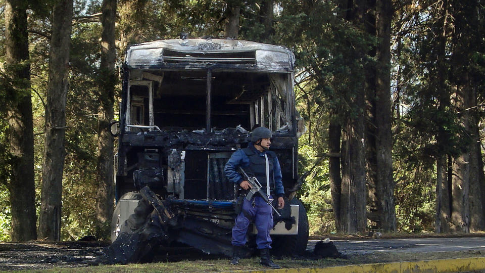 NYTT ANGREP: En politimann st�r vakt ved en utbombet politibil etter dagens bakholdsangrep som krevde minst ti polimenn livet. Foto: AFP