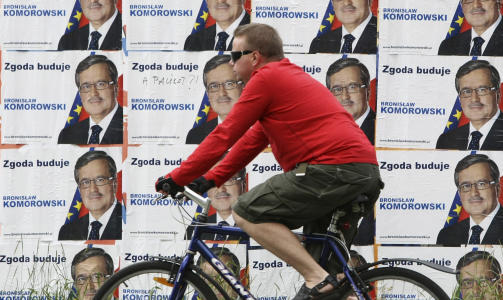 LEDER: En syklist passerer valgplakater med bilde av venstresidens presidentkandidat Bronislaw Komorowski i Warszawa. Valglokalene i Polen �pnet tidlig s�ndag morgen, og Komorowski leder p� meningsm�lingene. Foto: REUTERS / Kacper Pempel / SCANPIX