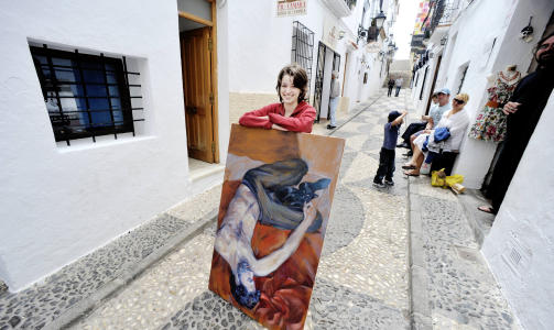 KUNSTNERBYEN: Denise Serranos fra Columbia viser fram et ferskt maleri i hovedgata Calle Mayor. Foto: JOHN TERJE PEDERSEN
