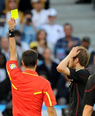 FORTVILELSE: Dommer Ravsjan Immatov (Usbekistan) gir Thomas M�ller gult for en hands. Det tyske vidunderet fortviler  - han g�r glipp av semifinalen. Foto: AFP