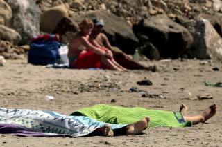 ITALIA: Dette bildet fra sommeren 2008 sjokkerte Europa. Det viser badegjester i Torregaveta som tilsynelatende ikke brydde seg nevneverdig om de to druknede romajentene p� 15 og 13 som l� p� stranda. Foto: EPA/CESARE ABBATE