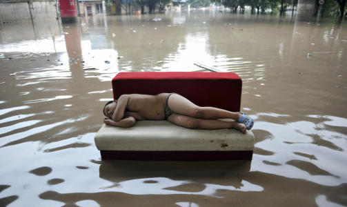 MILLIONER RAMMET:  Flere millioner mennesker er blitt husl�se som f�lge av flommen. Her hviler et barn ut p� en sofa i de oversv�mte gatene. Foto: Scanpix