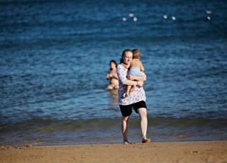 P� STRANDEN: Martin synes vannet er veldig kaldt. Her b�rer mamma ham tilbake til den gode og varme sanden. FOTO: JON TERJE HELLGREN HANSEN