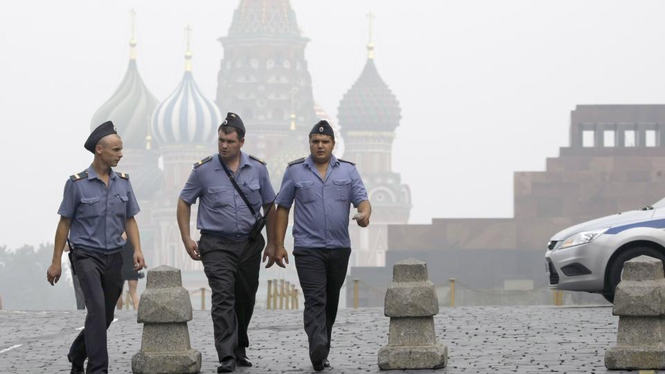 LAMMET AV R�YK:  Tre politimenn g�r over den r�de plass i Moskva. Byen er lammet av kveldene r�yk. Foto: AP Photo/Misha Japaridze