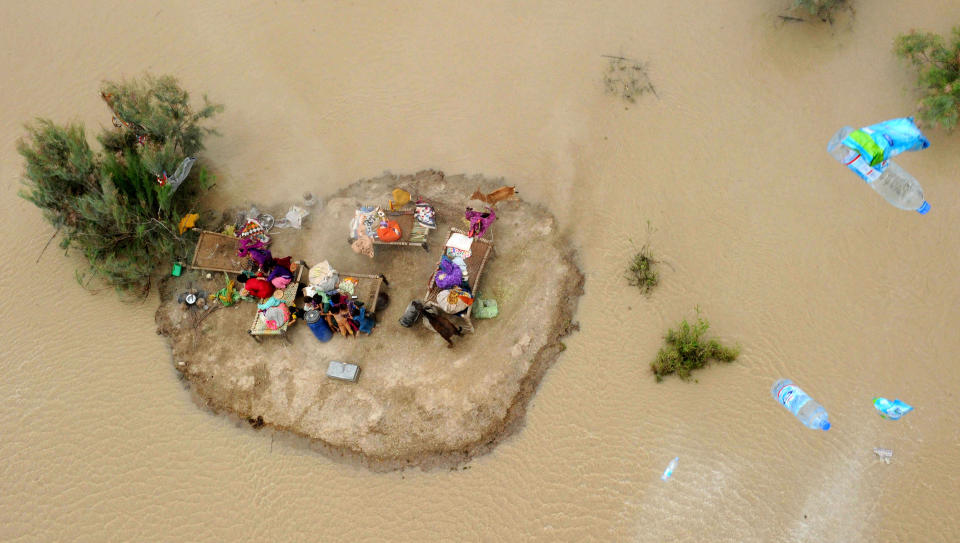 STRANDET: Flere barn og noen voksne er strandet p� denne �ya, som er dannet i havet av flomvann og gj�rme i pakistanske Sukkur. Foto: ASIF HASSAN/AFP