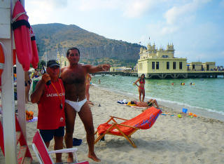  MONDELLO:   Salvatore (livredder) st�r det p� den r�d skjorta til Toto, som passer p� alt som foreg�r p� sj� og strand. Badeslott med restaurant og badeboder i bakgrunnen. Foto: Kirsten Margrethe Buzzi