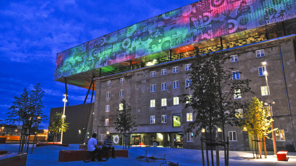 Lyser opp: Rockheim er godt synlig etter at sola har g�tt ned, til b�de glede og frustrasjon for Trondheims innbyggere. Veggenes CD-cover i keramisk print kan byttes ut med nye ansikter etter som �rene g�r. Parken nedenfor har allerede blitt popul�r blant skatere og BMX-ere, med sitt spesielle, b�lgende betongdekke. Foto: Anniken Zahl Furunes.