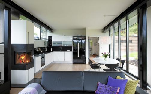 STORSTUE: Peisen ligger midt i rommet og er synlig b�de fra salonggruppe og spiseplass. Sofa fra Skeidar. Allrommet er smalt og langt, men glassflatene og takh�yden bidrar til at det oppleves st�rre. Foto: Espen Gr�nli