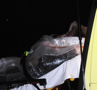 VENTET P� HOLME: Niels H�jlund (24) sto i timevis p� holmen Sand�ya og ventet p� hjelpen - som endelig kom i 00.30-tida. Her fraktes han inn i ambulansen p� Farestad etter � ha blitt hentet av b�t. Foto: MARTIN N�SS KRISTIANSEN/LINDESNES AVIS
