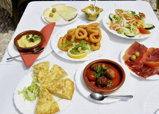 P� MENYEN:  Tradisjonelle  tapas st�r ogs� p� menyen. Her er det jamon serrano (spansk skinke)  til venstre, bakerst queso manchego (mangcho ost) og foran st�r st�r en bolle med albondigas (kj�ttboller)  og tortilla espanola  (spansk bondeomelett).  Bakerst  humus, aioli(hvitl�smajones) og salat. Foto: JOHN TERJE PEDERSEN/ Dagbladet