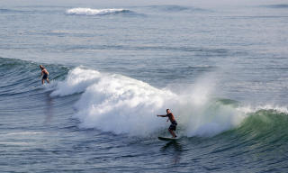 SURFER P� EARL: Mens andre pr�ver � komme seg unna kysten, str�mmer ivrige surfere til for � f� en smak av noen store b�lger. Foto:  REUTERS/Richard Clement/Scanpix