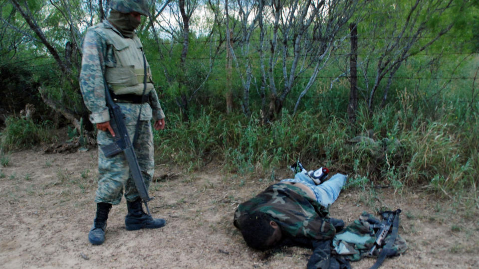 DREPT: En soldat st�r ved siden av en av de 27 mennene som er drept. De ble drept da h�ren kom over en treningsleir til den kriminelle grupperingen Zetas. Foto: AFP PHOTO/Dario Leon/Scanpix