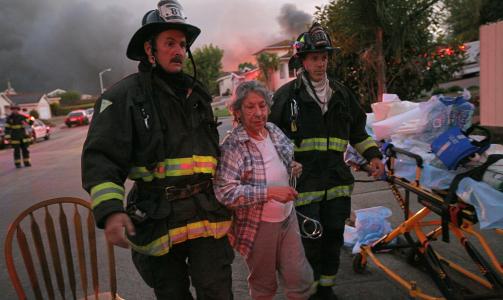REDDET: En evakuert kvinne reddes fra flammene i San Bruno, California. Foto: AP/Scanpix
