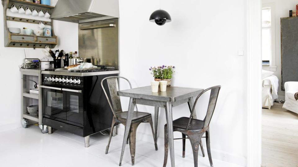 INDUSTRIELT UTTRYKK: Kj�kkenet ligger i forbindelse med stuen, adskilt av en glassd�r. Den store Ilve-komfyren ble utgangspunktet for innredningen av kj�kkenet, og den  definerte ogs� den litt r�, industrielle stilen. Det lille spisebordet er fra Fil de Fer, stolene fra Butik Sophie, og lampen er Pantons Flower Pot.  FOTO: Linnea Press